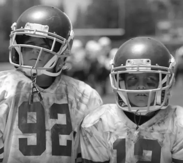 Two football players in helmets are standing together.